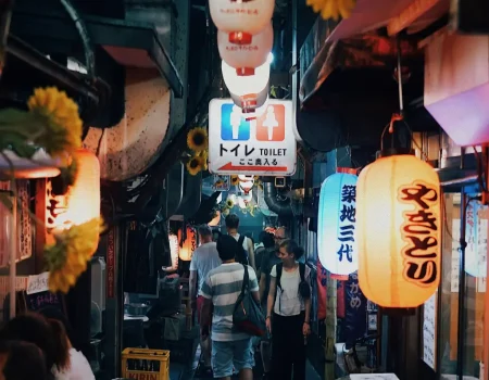 Rue animée de Tokyo avec enseignes lumineuses et street-food japonaise